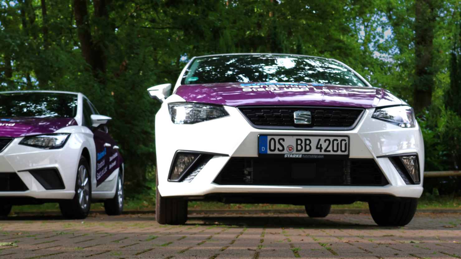 Bild mit zwei Autos der Diakonie Sozialstation Belm-Bissendorf. In der linken oberen Ecke ist ein Button, der besagt "$0 Jahre Sozialstation Belm-Bissendorf"