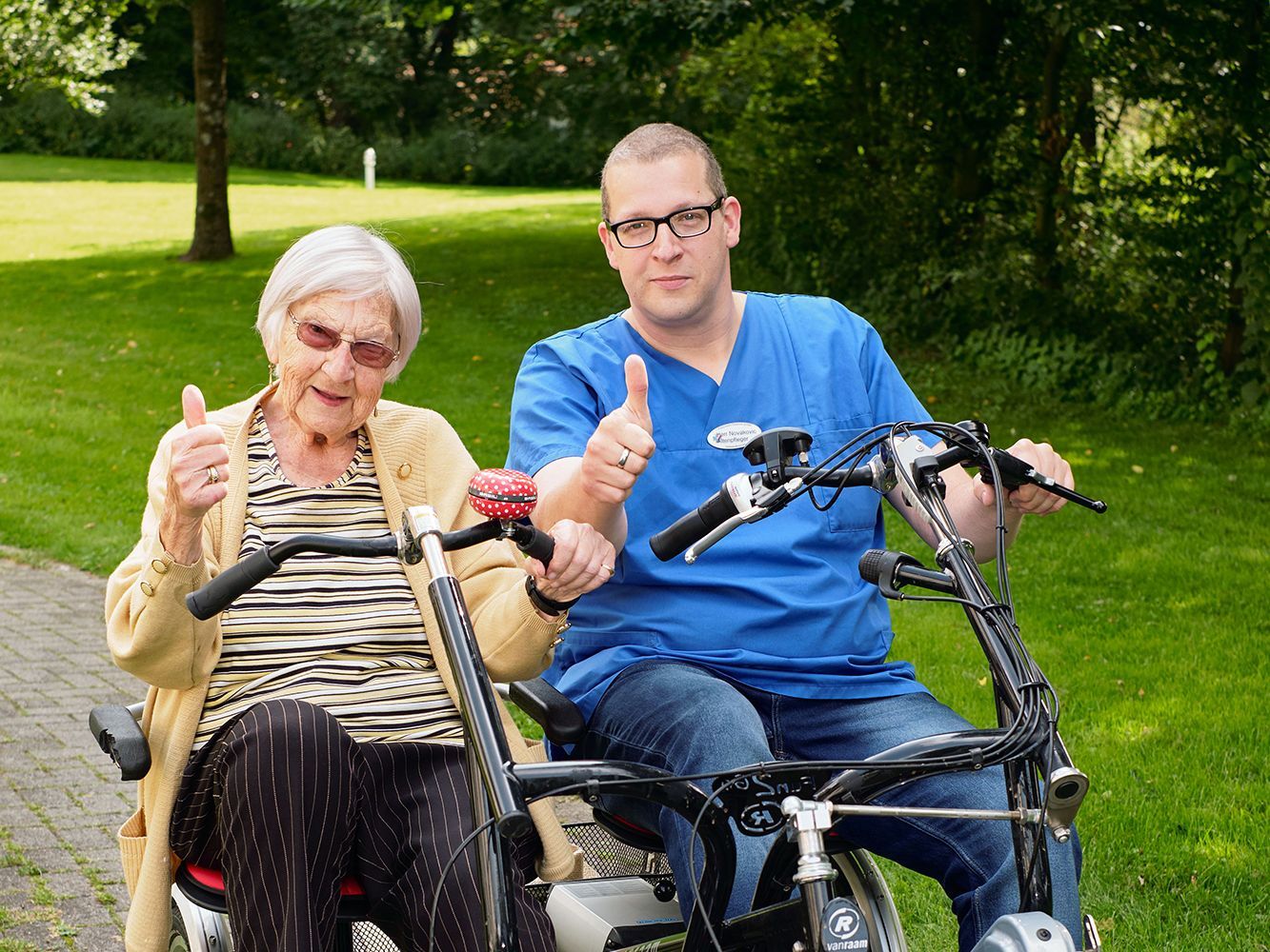 Eine Bewohnerin und ein Pfleger das Hermann-Bonnus-Hauses, fahren auf einem Tandem-Sitz-Fahrrad