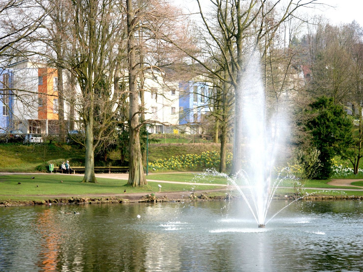 Blick auf das Haus am Kasinopark von den Parkanlagen des Kasionpark und dem See mit Springbrunnen